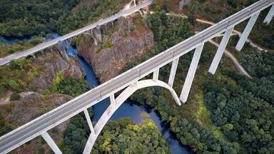 Eine große Brücke überspannt einen Fluss in bewaldeter Landschaft.