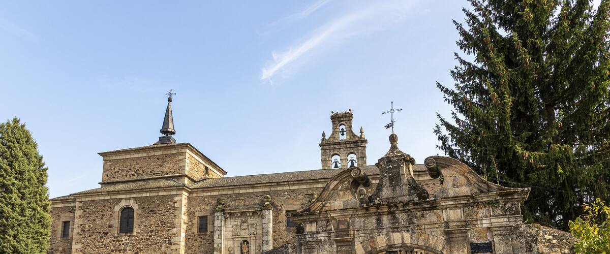 A historic stone building with a bell tower and a large arched entrance gate.