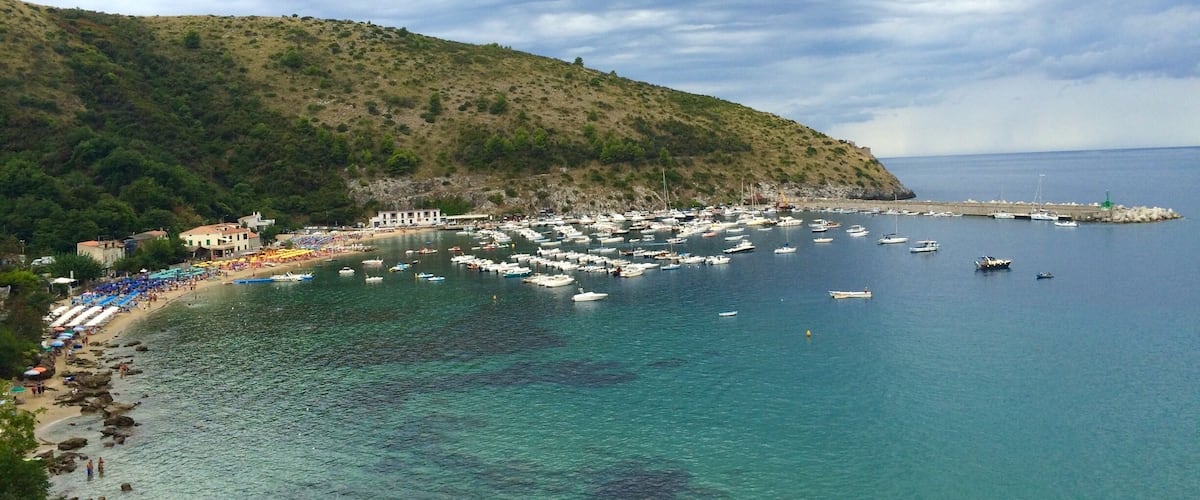 A coastal town with a beach, boats, and a rocky shoreline.