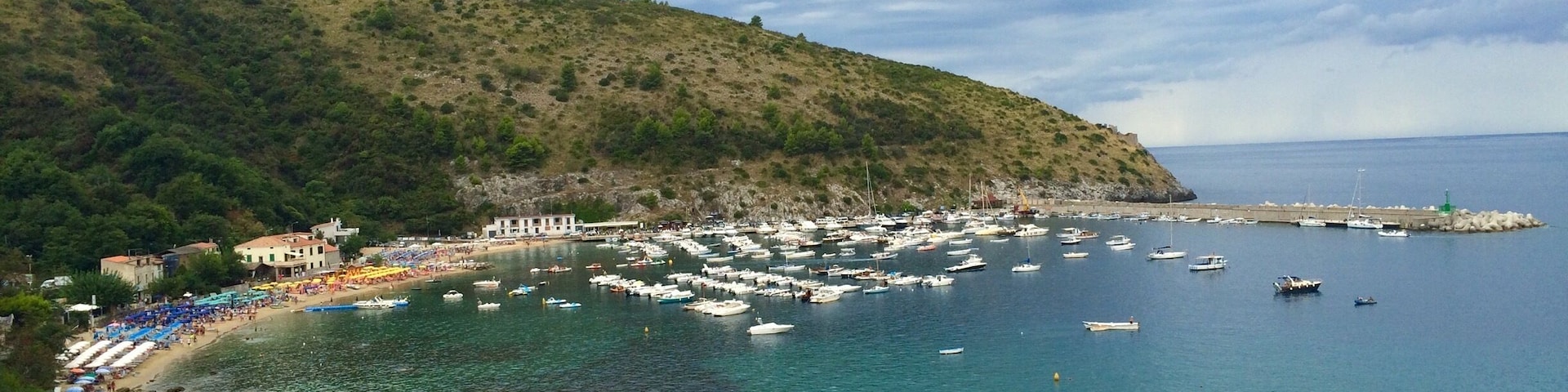 A coastal town with a beach, boats, and a rocky shoreline.