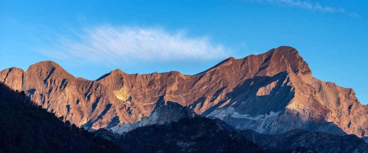 A rugged mountain range with sharp peaks and deep valleys under a clear blue sky.