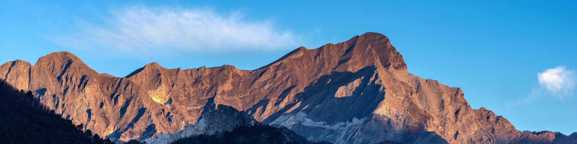 A rugged mountain range with sharp peaks and deep valleys under a clear blue sky.