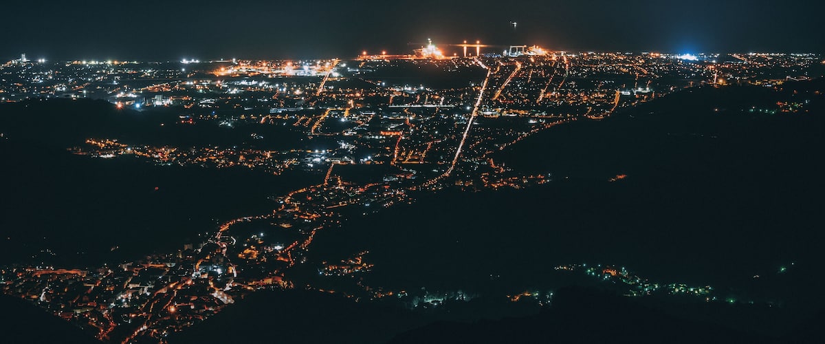 A nighttime aerial view of a city with illuminated streets and buildings.