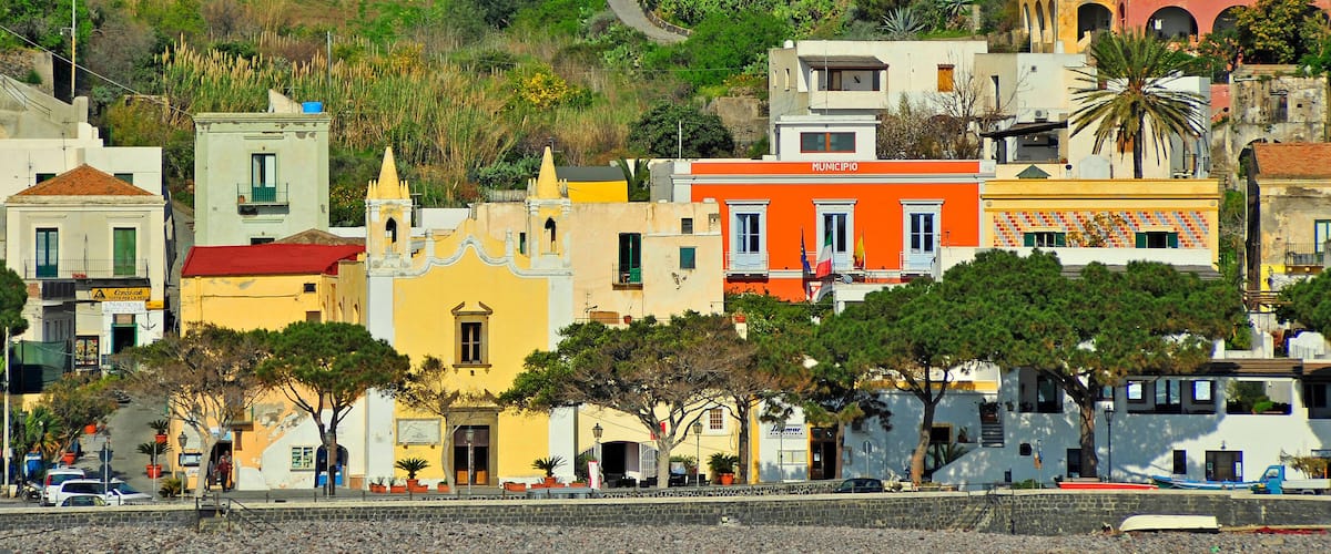 A coastal town with colorful buildings, a church, and a rocky shoreline.