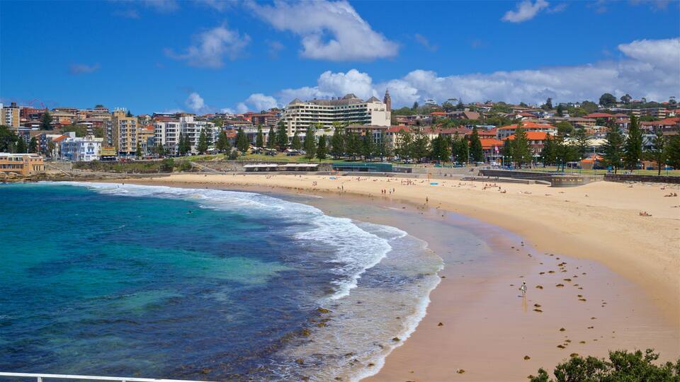 A coastal cityscape with a sandy beach, clear blue waters, and a prominent building with a clock tower.