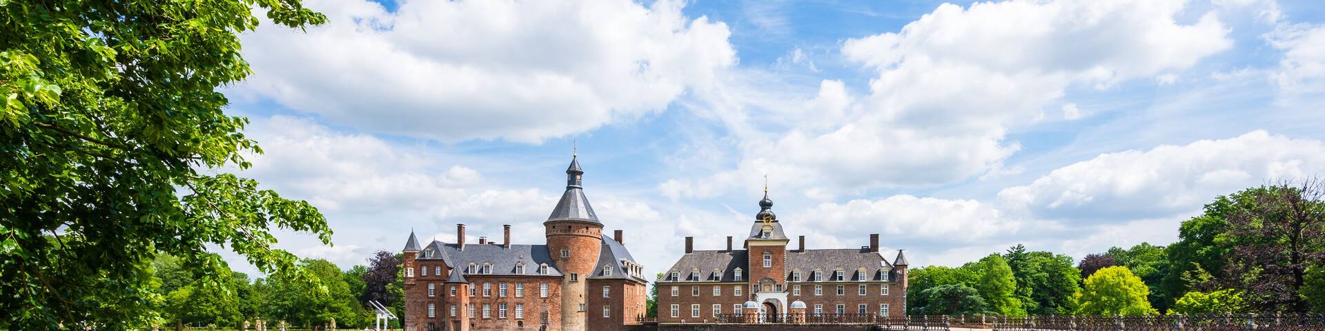 A historic castle with a moat and lush greenery.