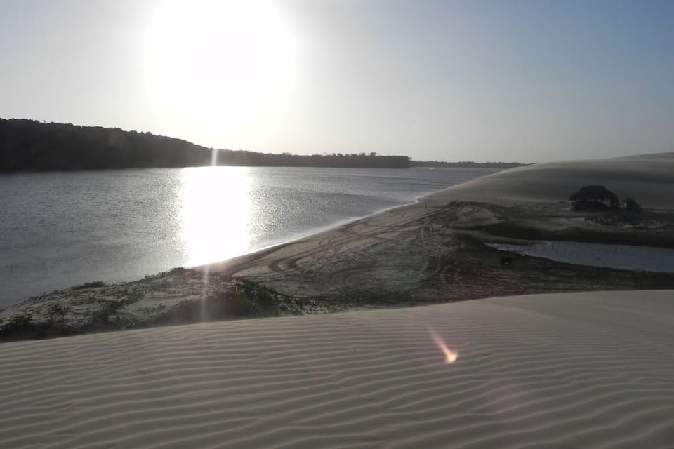 A desert landscape with sand dunes and a body of water.
