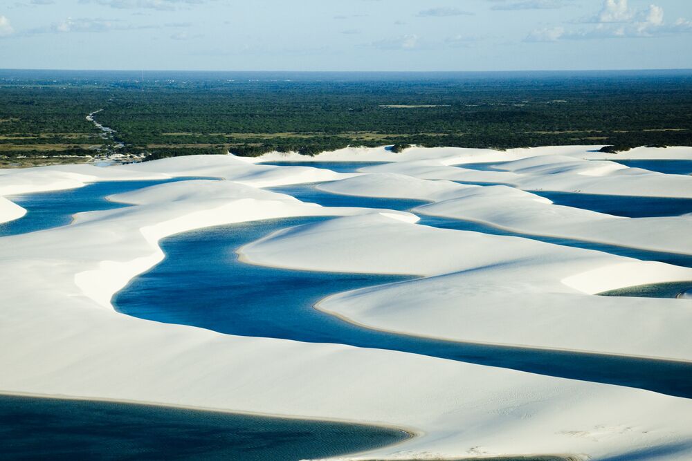 A vast desert landscape with white sand dunes and blue water channels.