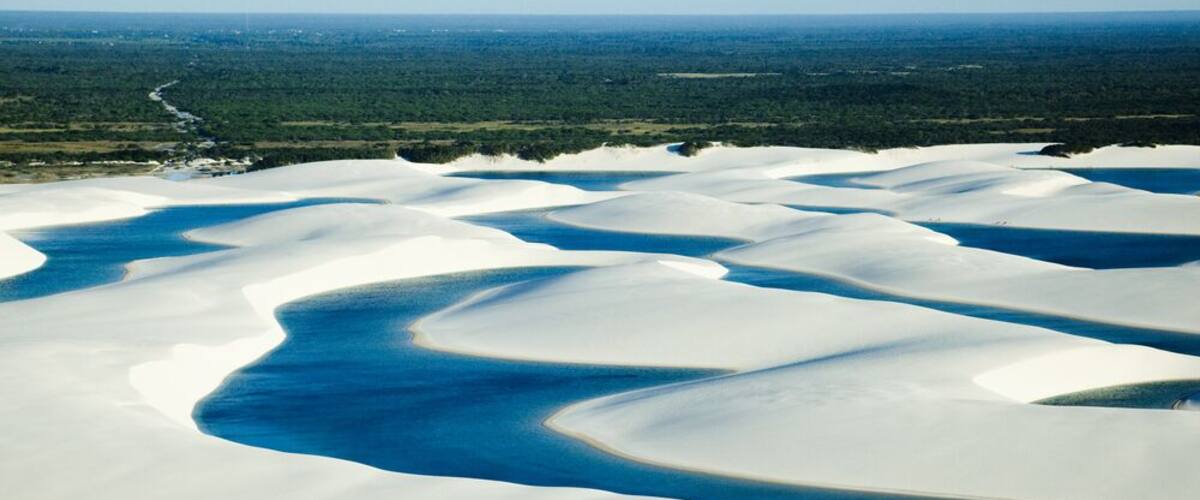A vast desert landscape with white sand dunes and blue water channels.
