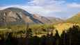 A mountainous landscape with dense forests and a clear sky.