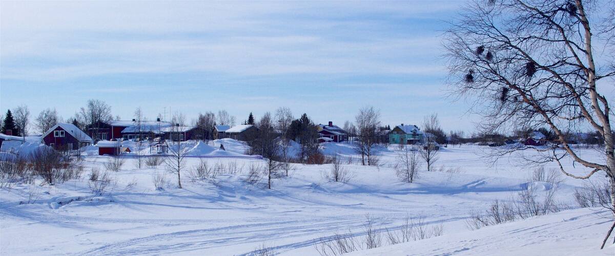A snowy landscape with houses and a clear sky.