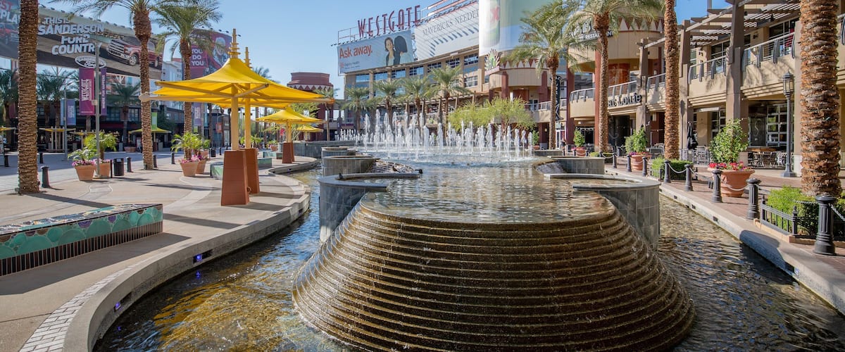 A water fountain with multiple tiers, palm trees, and a Westgate sign in the background.