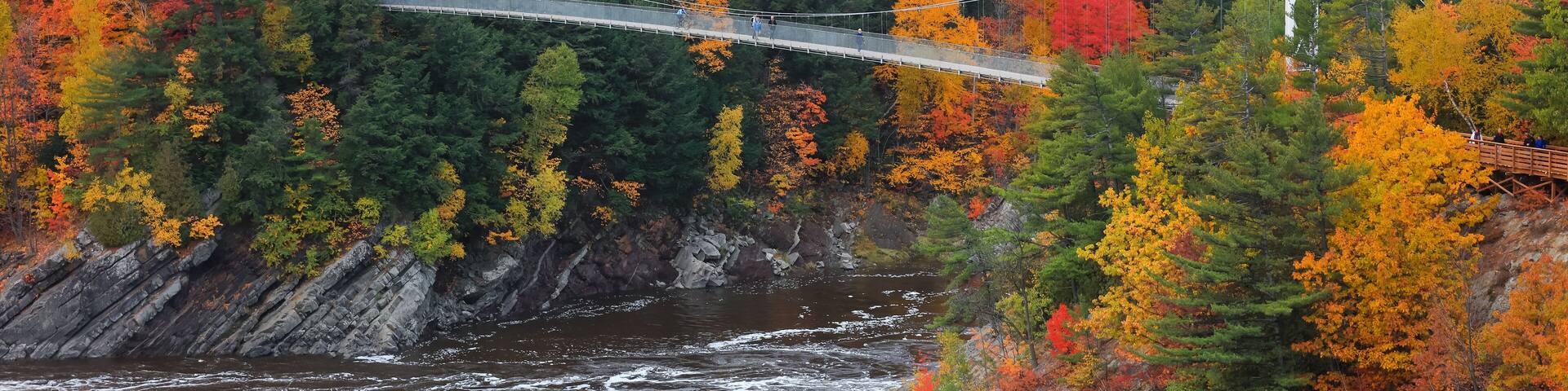 Chaudière River Suspension Bridge at Chaudière Falls Park surrounded with fall foliage.