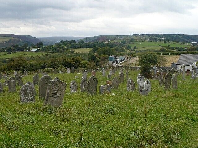 View from St Sannan's churchyard, Bedwellty Just beyond the churchyard on the right is a greyhound racing track. The Rhymney Valley can be seen at the upper left with the peaks of the Brecon Beacons on the horizon.