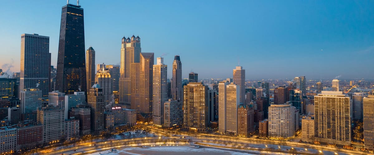A city skyline with tall buildings and a frozen river.