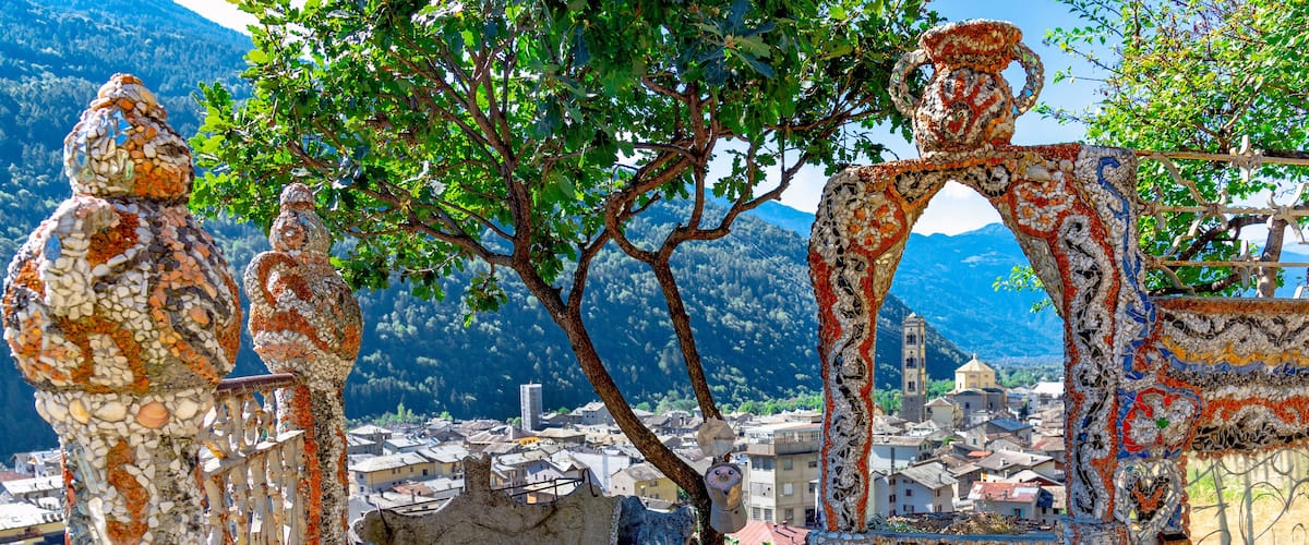 Mosaic sculptures and a view of a town with mountains in the background.