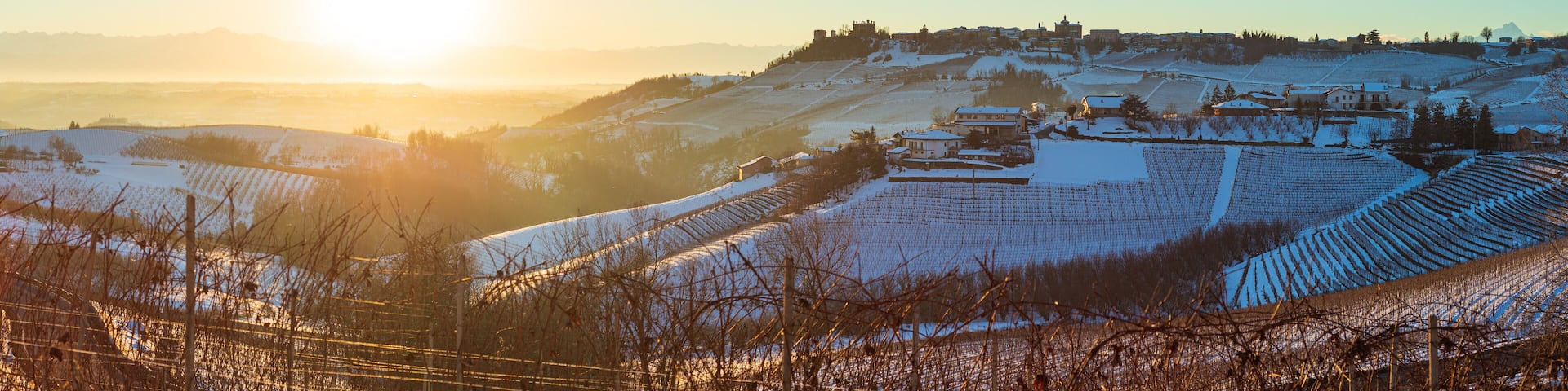 Italy Piedmont: Barolo wine yards unique landscape winter sunset, Novello medieval village castle on hill top, the Alps snow capped mountains background, italian historical heritage grape agriculture