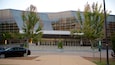 A modern building with a glass facade and a parking lot.