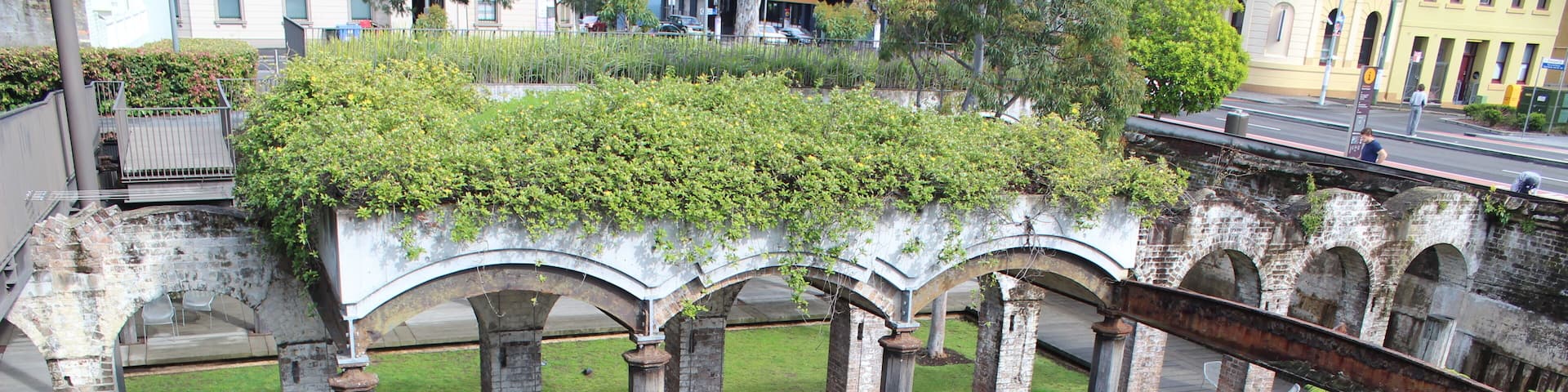 An arched structure with a pool and lush greenery.
