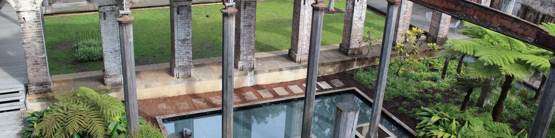 An arched structure with a pool and lush greenery.