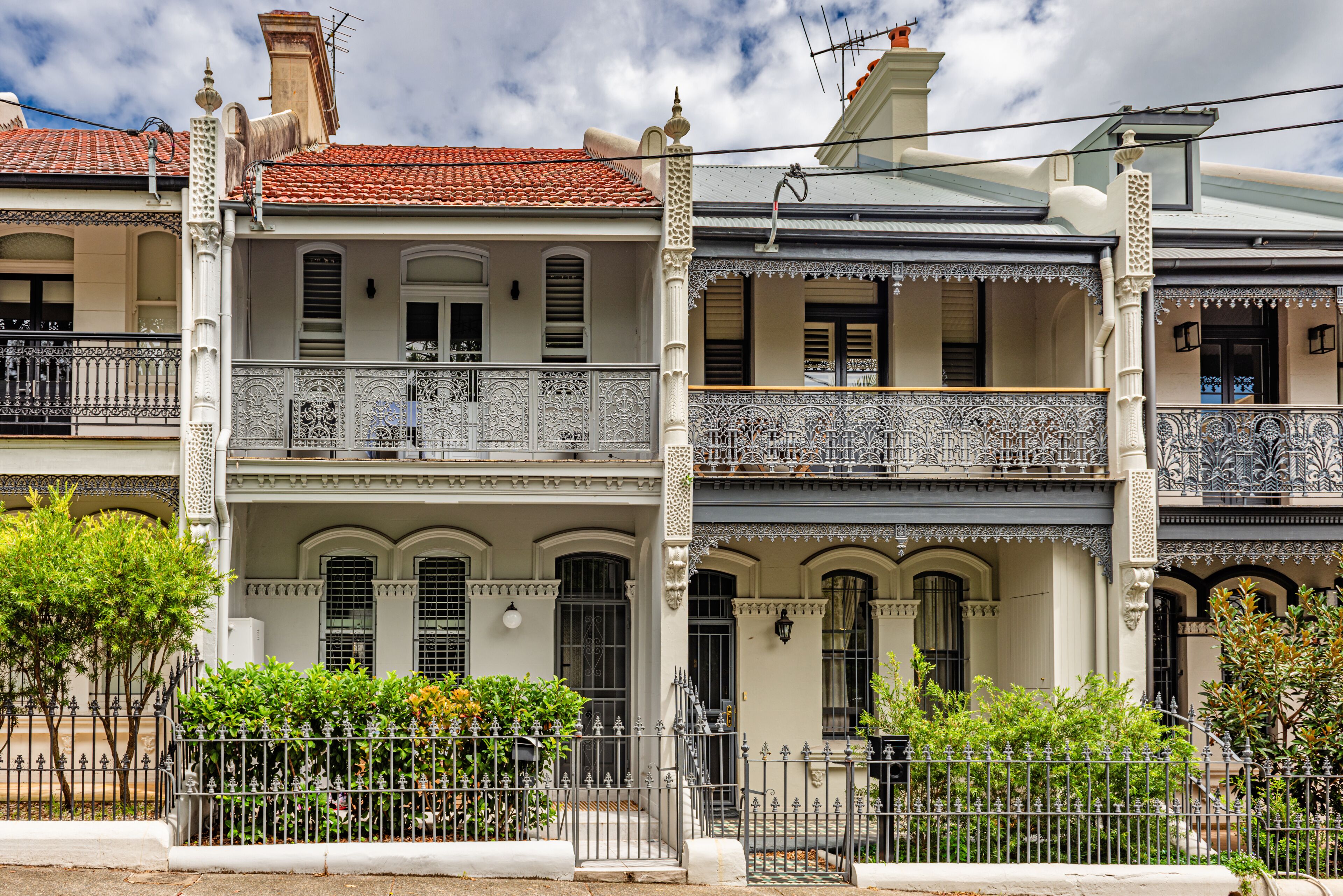 A row of colonial-style buildings with ornate balconies and a red-tiled roof.