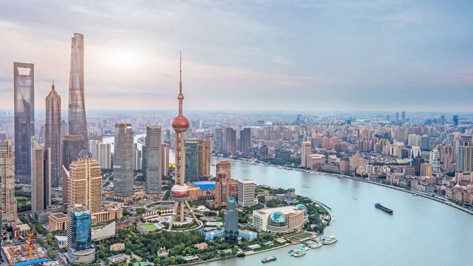 A cityscape with prominent skyscrapers, a distinctive tower with a spherical observation deck, and a river with boats.