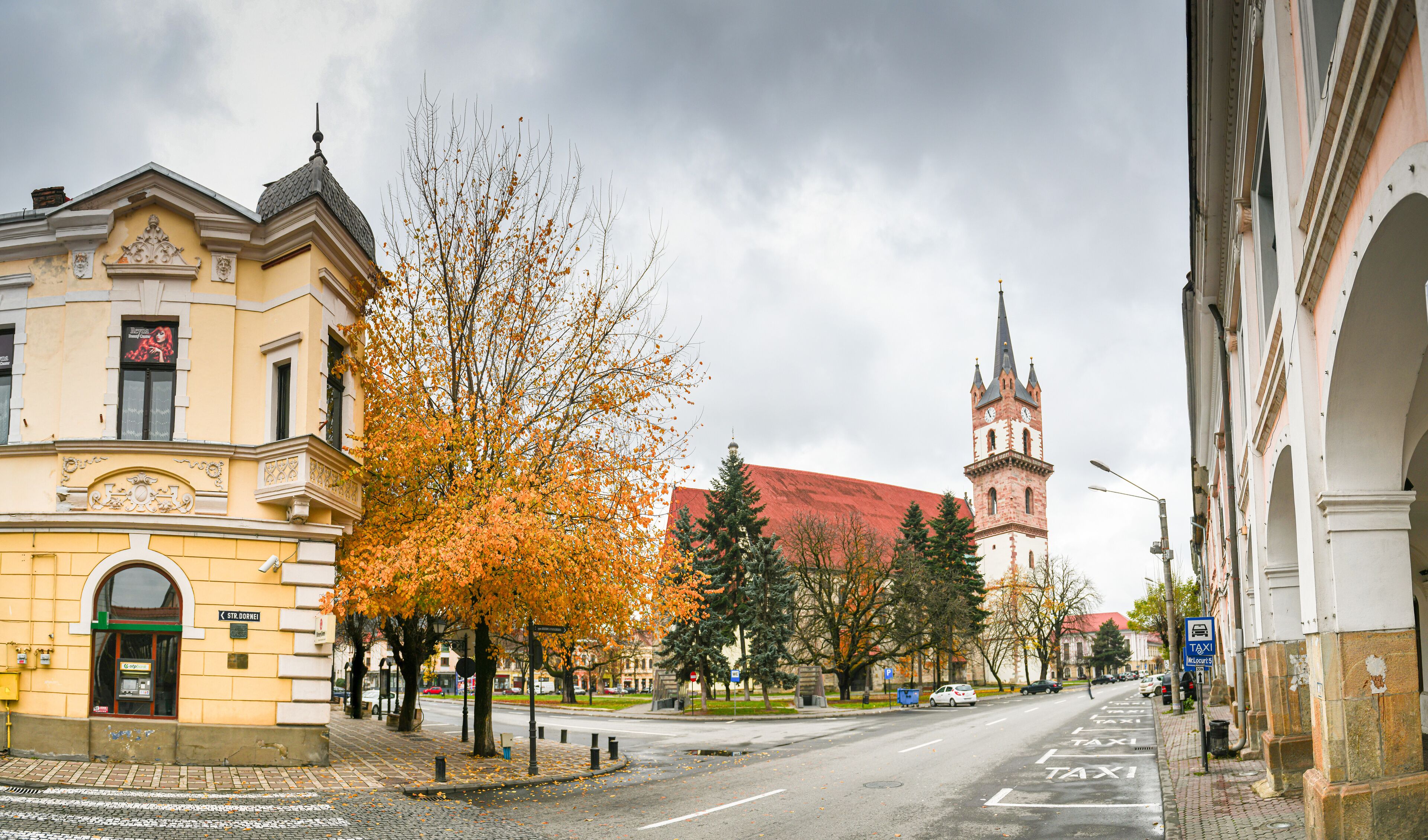 A street with autumn trees, a church, and historic buildings.