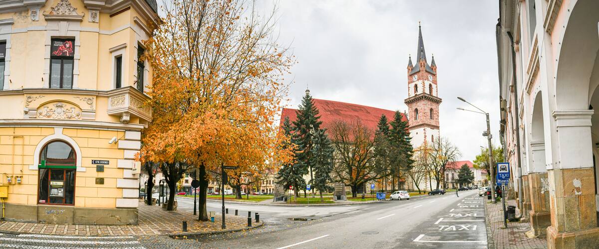 A street with autumn trees, a church, and historic buildings.