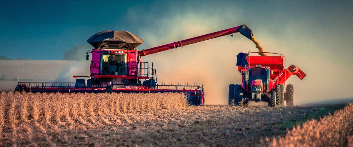 A combine harvester in a field with a dust cloud.
