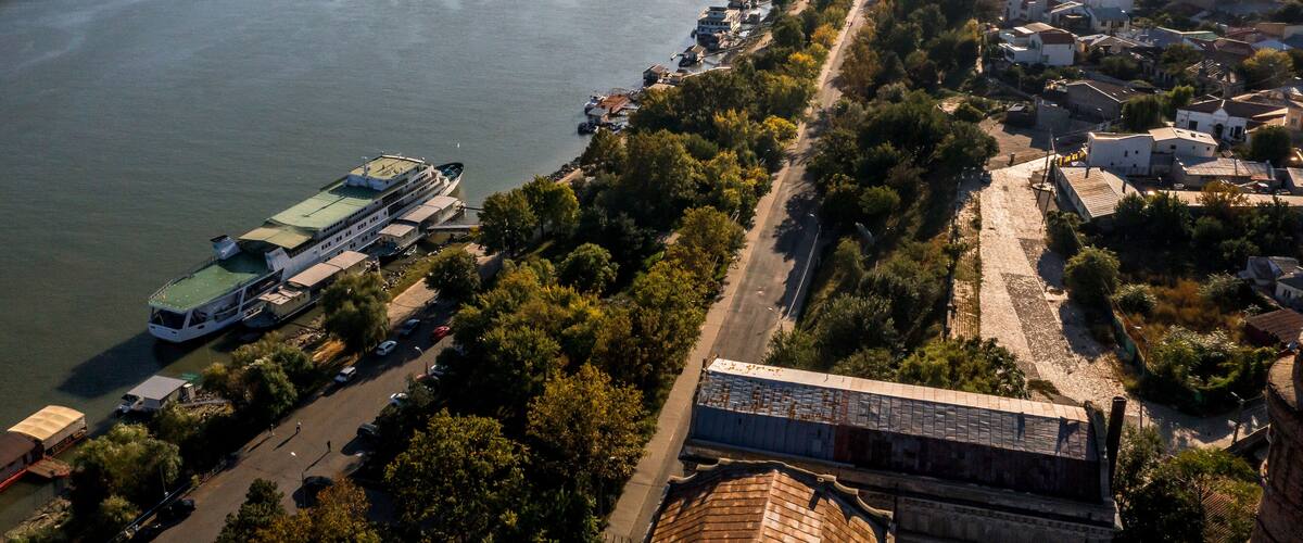 A river with a bridge, a cruise ship docked, and a cityscape with buildings and greenery.