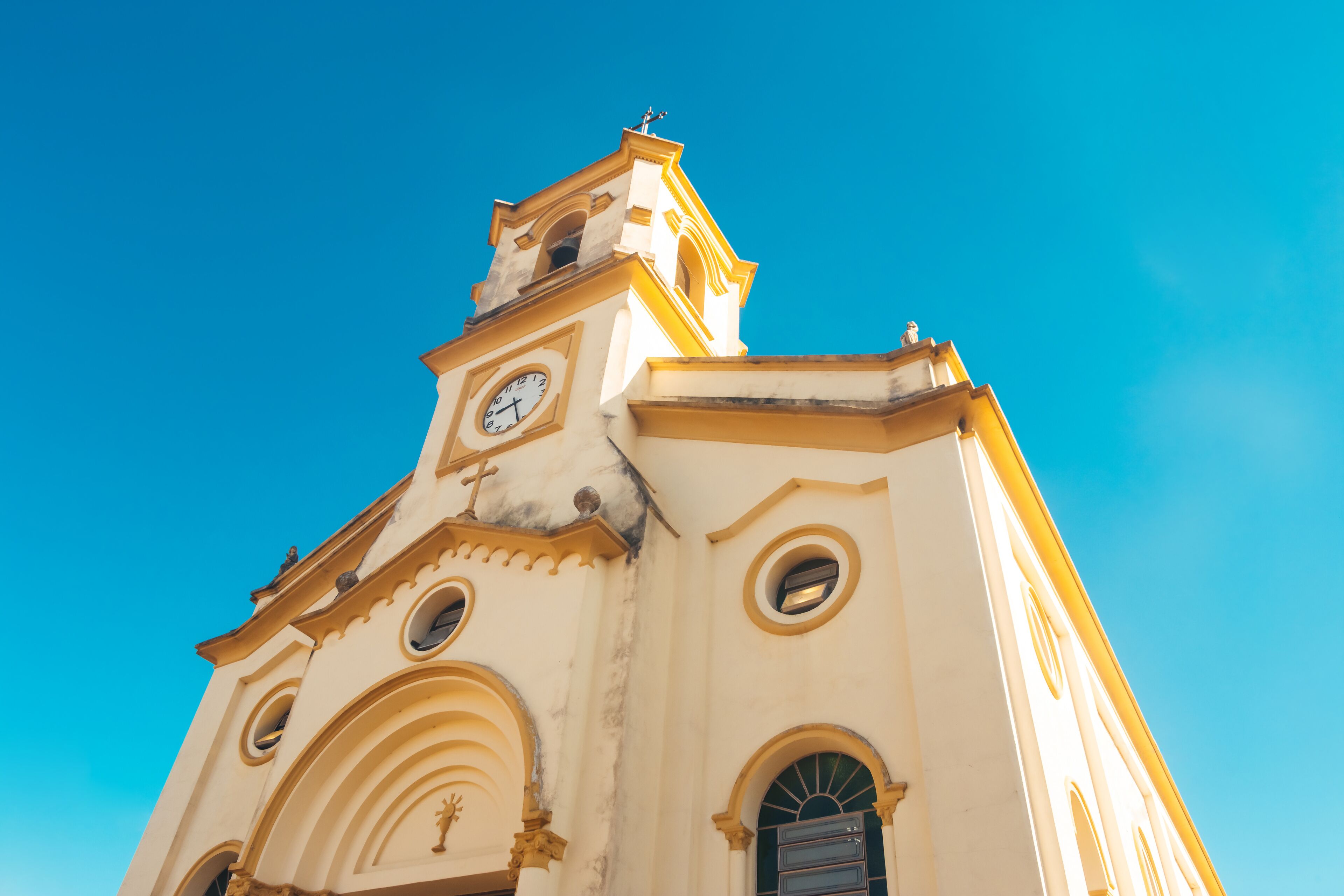 A church with a clock tower and arched windows against a clear blue sky.