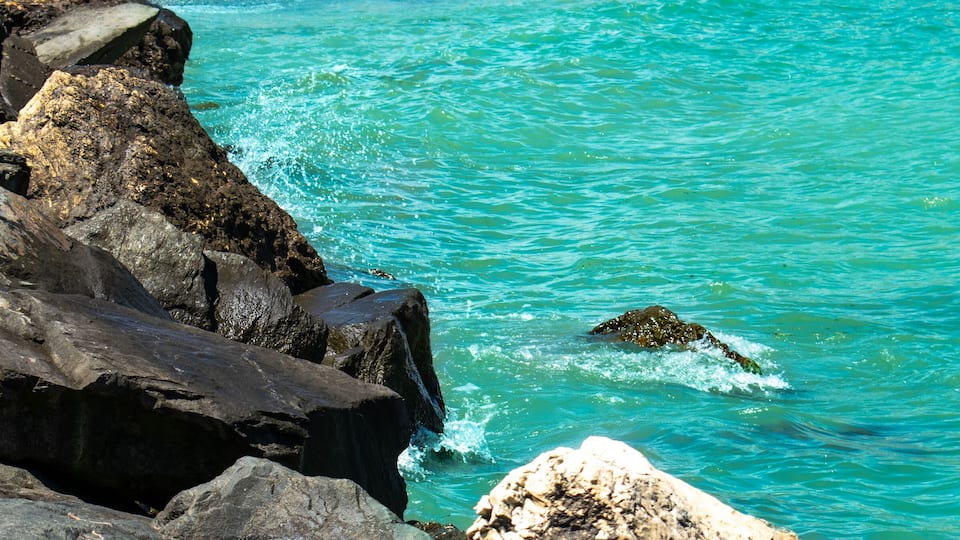 A rocky coastline with clear turquoise water and a small island.