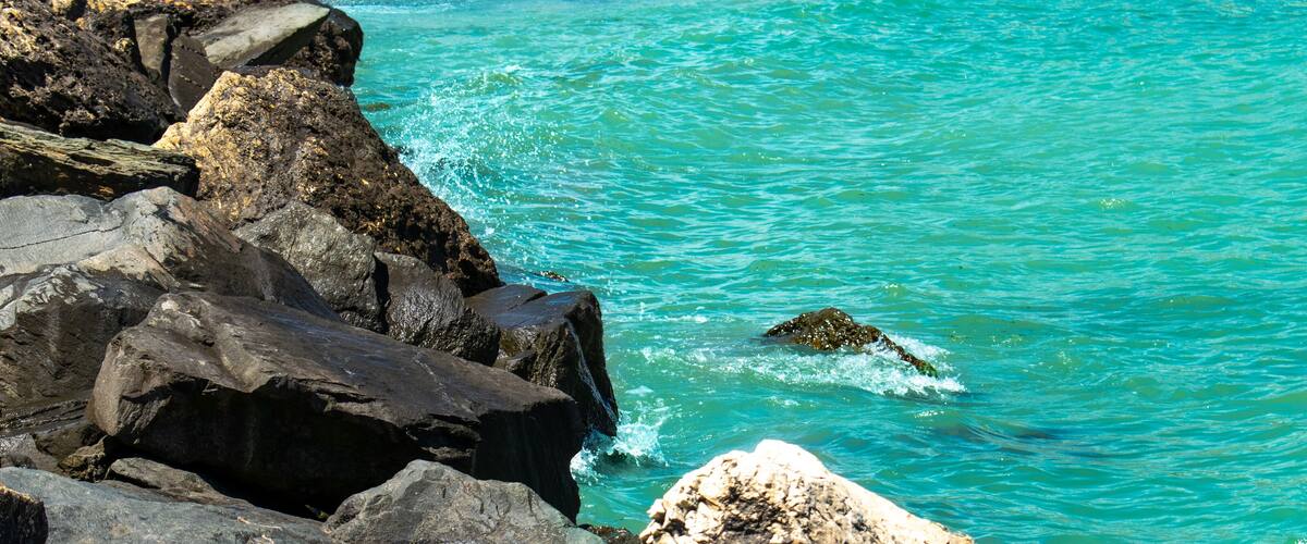 A rocky coastline with clear turquoise water and a small island.