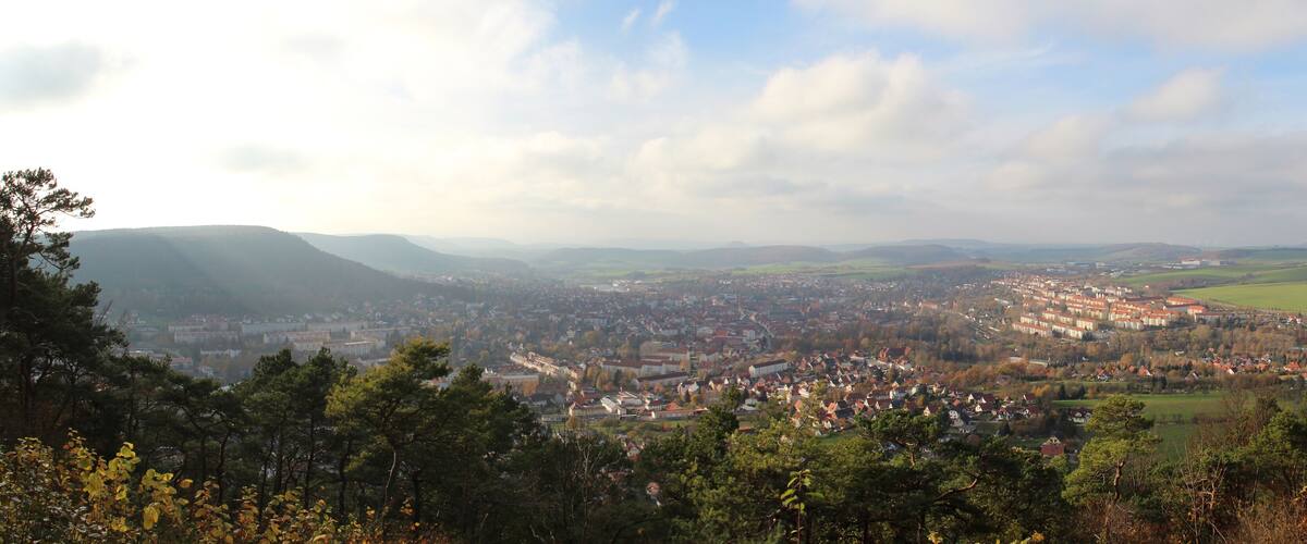 A panoramic view of a town nestled in a valley with surrounding hills and mountains.