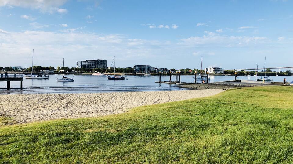 Ein Yachthafen mit Booten, ein Sandstrand und Gebäude im Hintergrund.