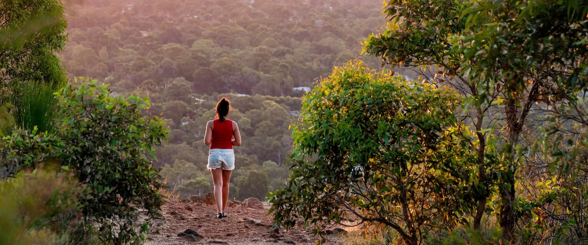 Girl watches sunset over the Perth City skyline from the Perth hills (Kalamunda Zig Zag). Perth, Western Australia, Australia.