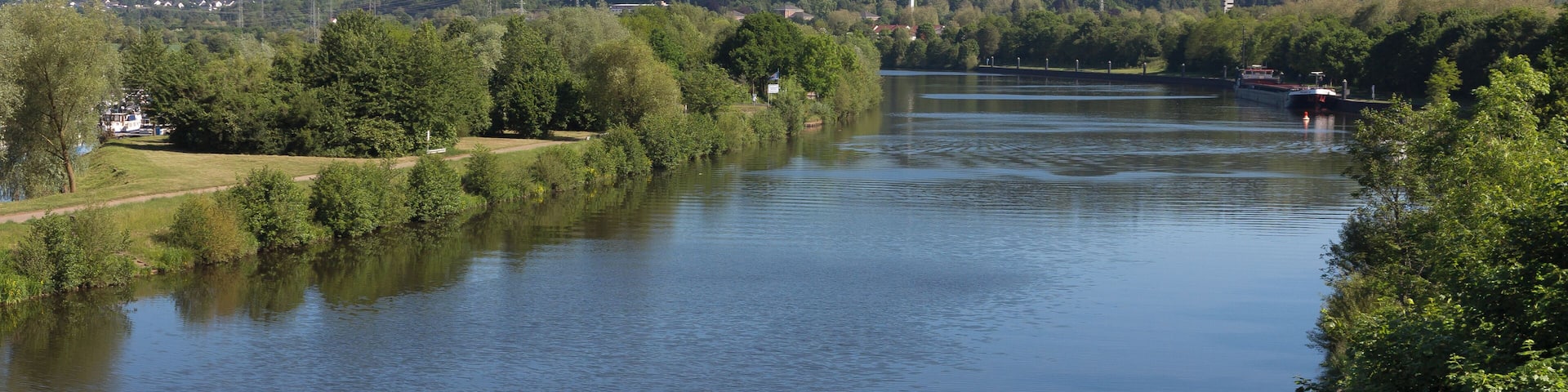 A river with a boat, surrounded by greenery and hills.