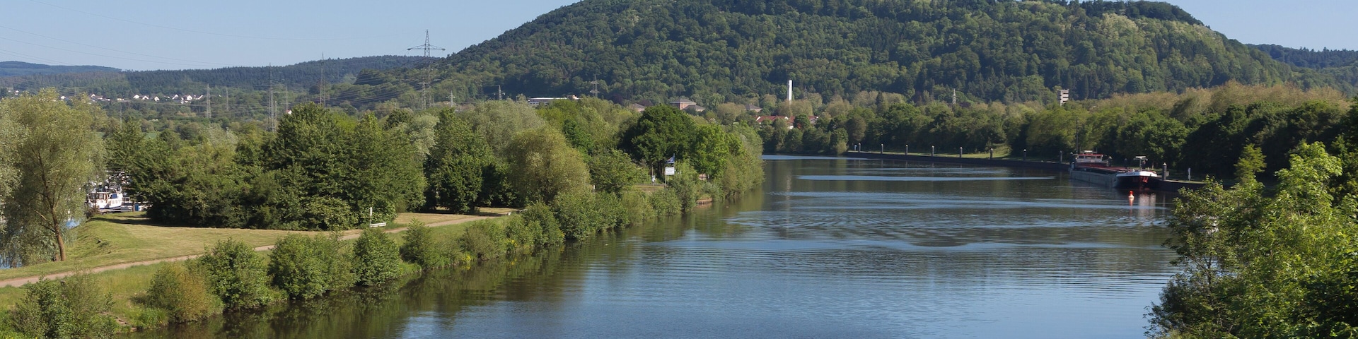 Un río con una barca, rodeado de vegetación y colinas.
