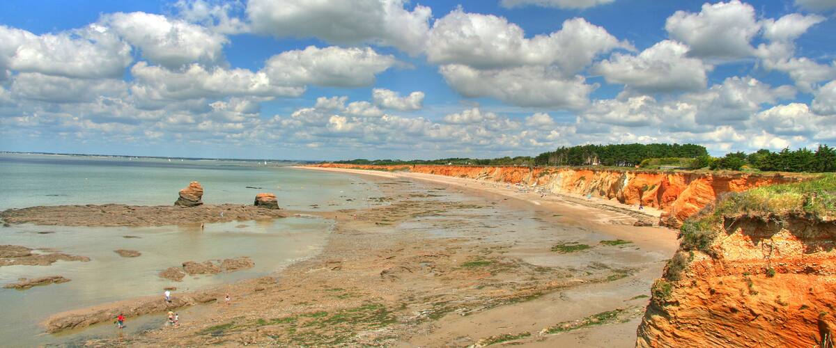 A coastal landscape with a sandy beach, rocky outcrops, and cliffs.