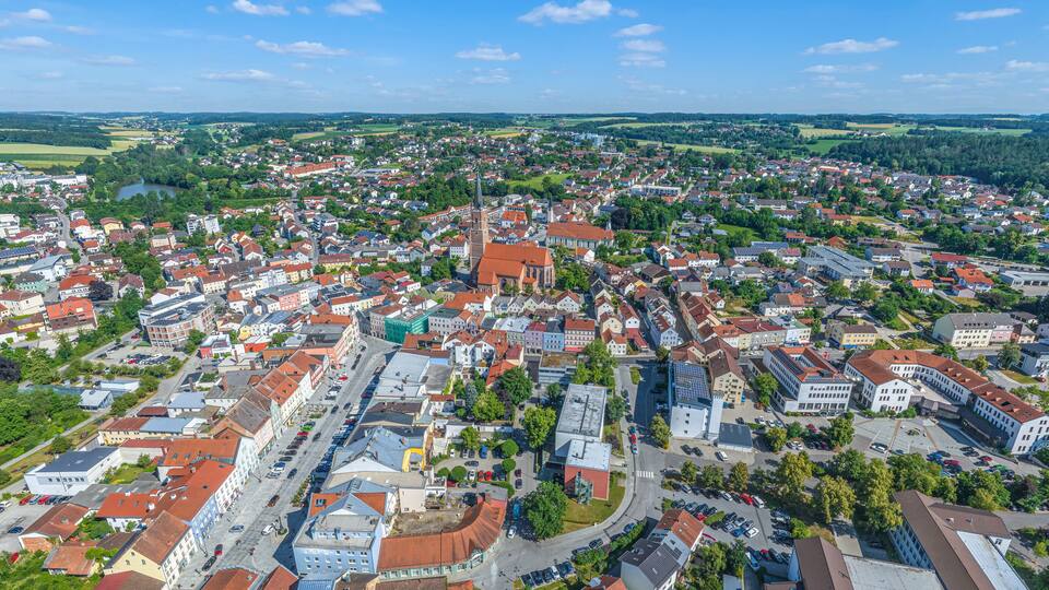 A town with a prominent church, a river, and surrounding greenery.