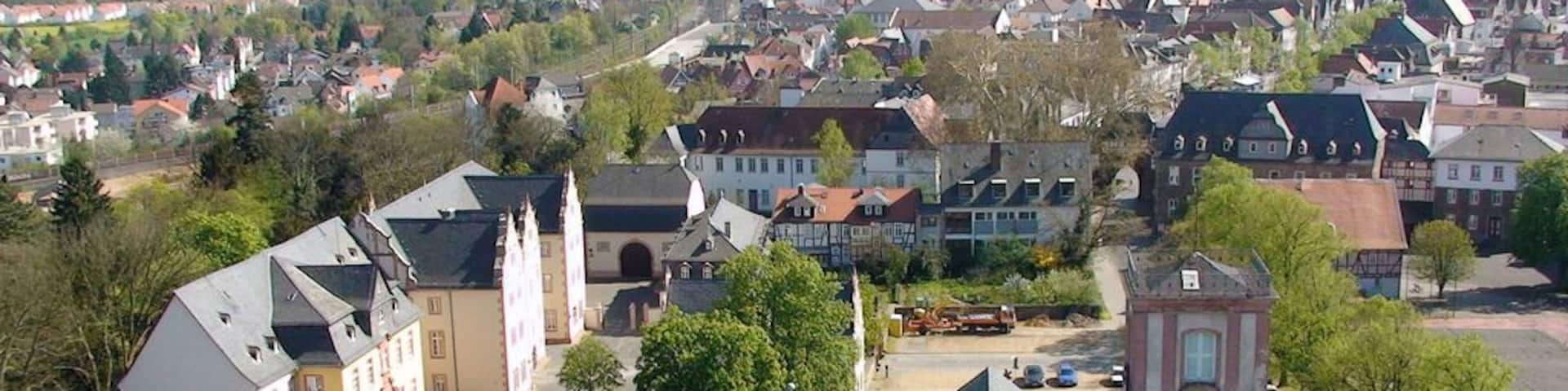 A town with historic buildings, a prominent clock tower, and a church with a tall spire.