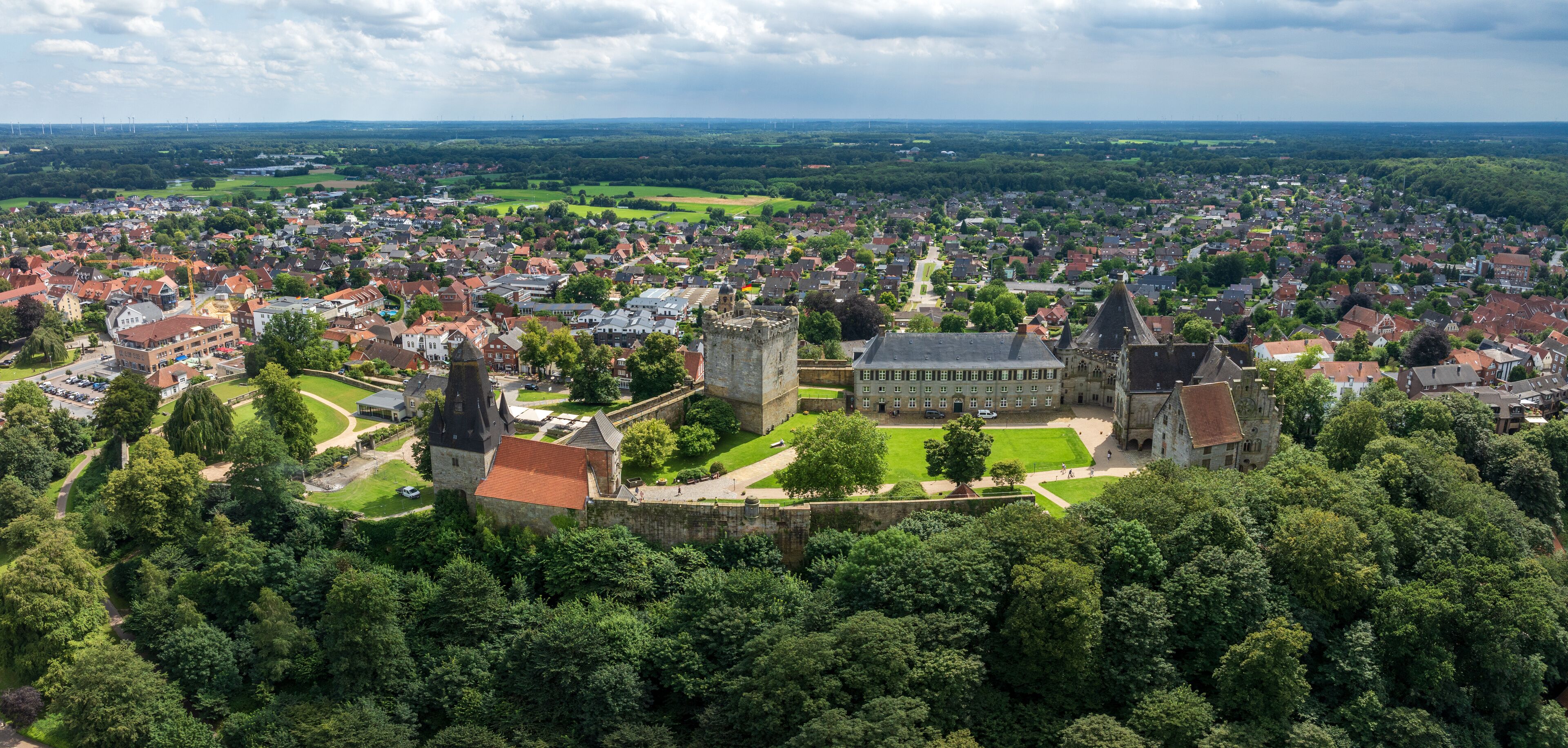 A historic town with a prominent castle, surrounded by lush greenery and a mix of residential and commercial buildings.
