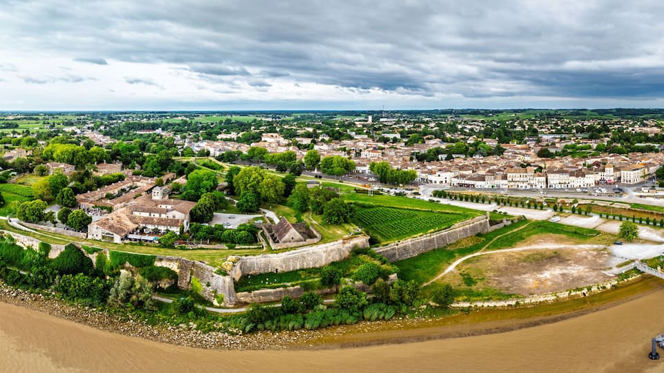 An aerial view of a historic town with a river, fortifications, and a bridge.