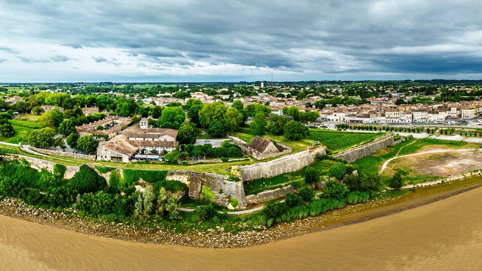 A coastal town with historic buildings, a river, and a bridge.