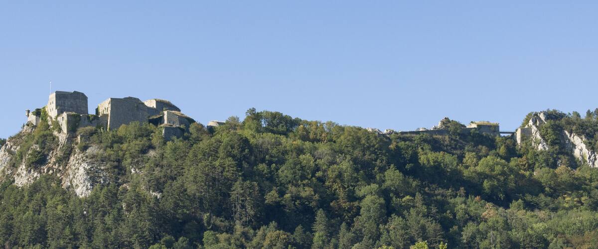 A mountainous landscape with ancient ruins perched on a cliff.