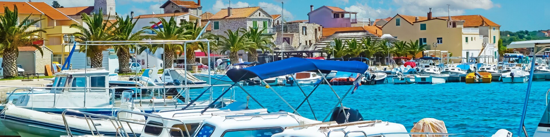 A marina with boats docked, a tower, and coastal buildings.