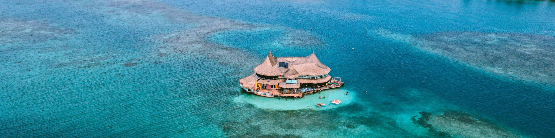 Vista aérea de una isla tropical con aguas turquesas cristalinas, rodeada de islotes más pequeños.