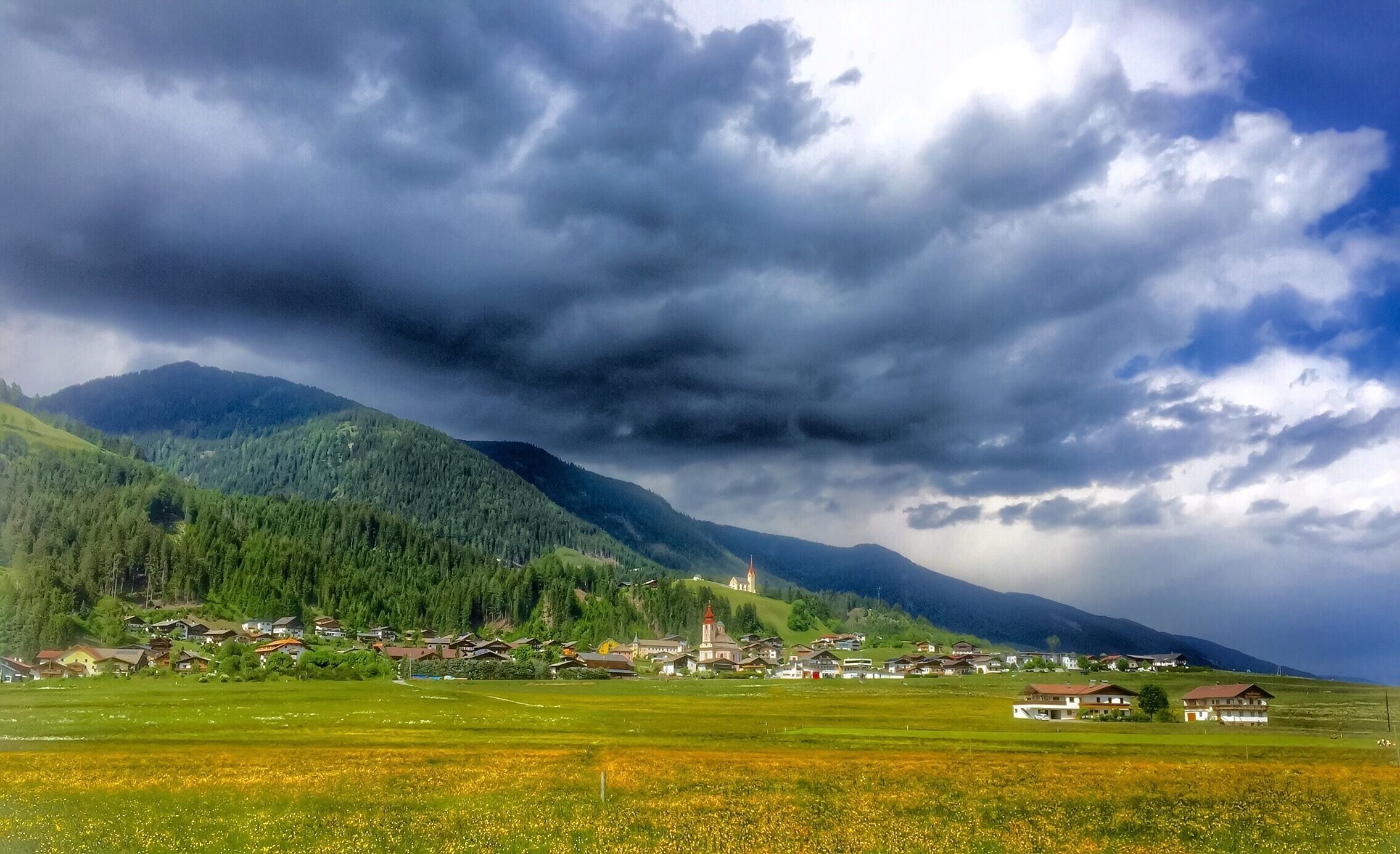 A village nestled in a valley with mountains in the background.