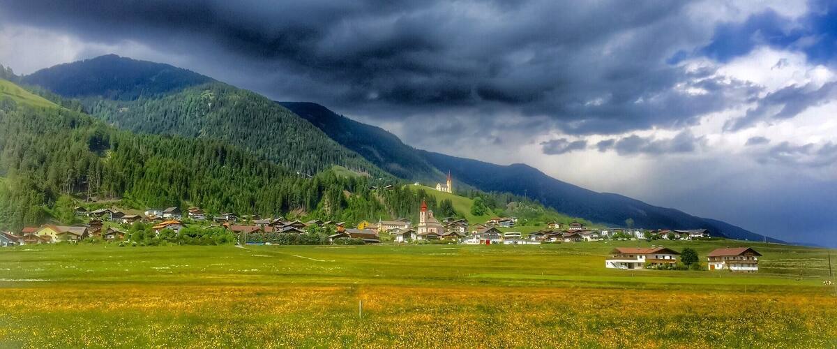 A village nestled in a valley with mountains in the background.