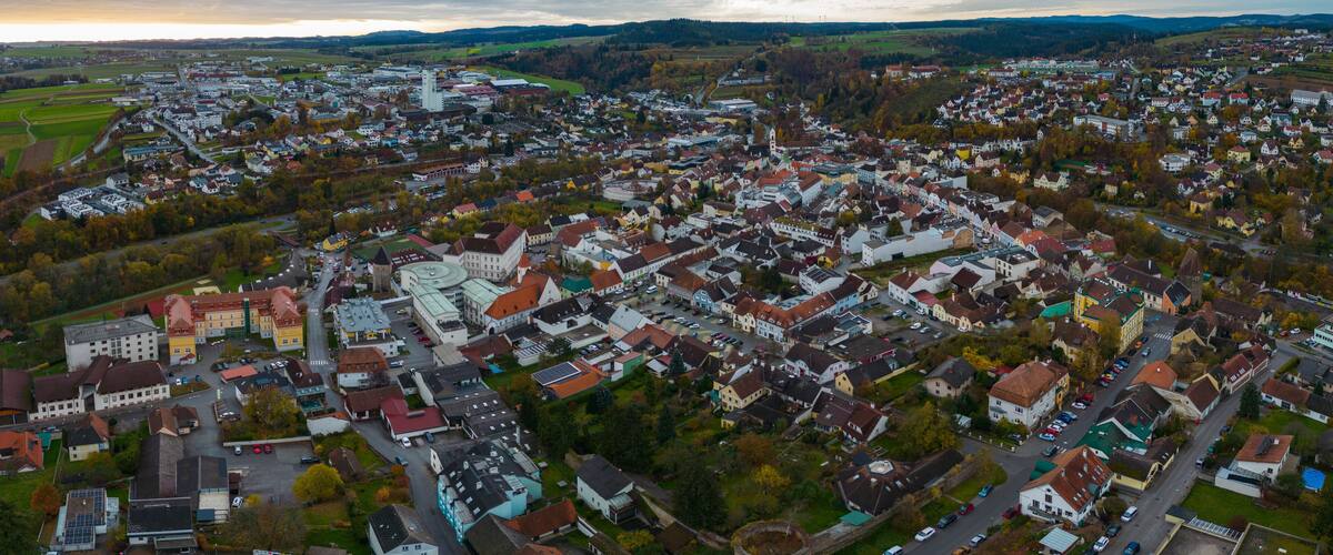 An aerial view of a town with a central round building, surrounded by residential houses and fields.